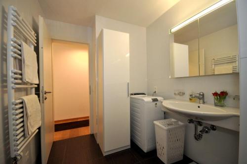 a white bathroom with a sink and a mirror at Rachögna in Scuol