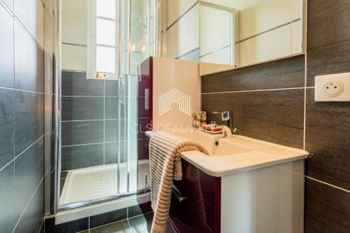 une salle de bain avec un lavabo et une douche dans l'établissement Appartement Les Mouettes C.L.S Deauville, à Deauville