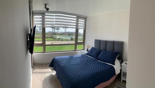 a bedroom with a blue bed and a window at Bello departamento av del mar in Coquimbo