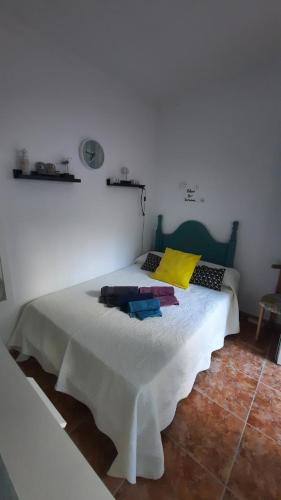 a white bedroom with a white bed with a yellow pillow at El patio de Villa Pancho in Chipiona