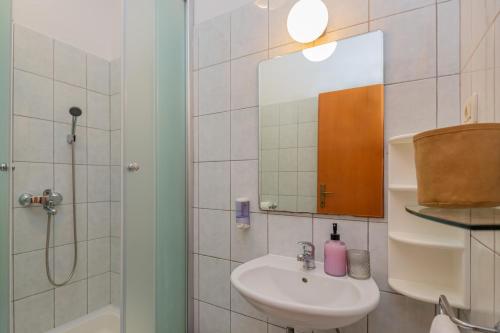 een badkamer met een wastafel, een douche en een spiegel bij Apartmani Grmoja in Baška Voda