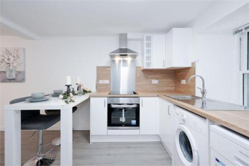 een witte keuken met een wastafel en een fornuis bij Royal Mile Old Town Apartment in Edinburgh