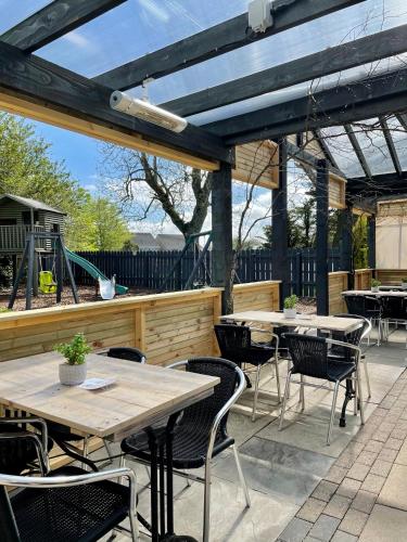 an outdoor patio with wooden tables and chairs at Newmachar Hotel in Newmachar