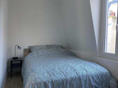 une chambre avec un lit avec une couette bleue et une fenêtre dans l'établissement Centre ville Granville à 50m de la mer - ANCV accepté, à Granville