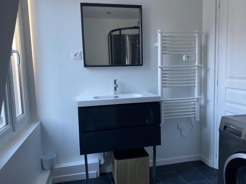 une salle de bain avec un lavabo et un miroir au mur dans l'établissement Centre ville Granville à 50m de la mer - ANCV accepté, à Granville