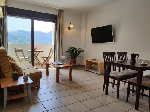 ein Wohnzimmer mit einem Sofa, einem Tisch und einem TV in der Unterkunft APARTAMENTOS SERRELLA - Rural Guadalest in Benimantell