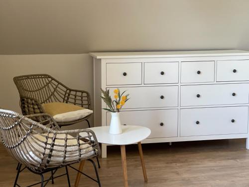 a white dresser and a chair and a vase with flowers at Willa Julianna in Mikołajki