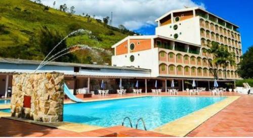 um hotel com piscina em frente a um edifício em FLATs CAVALINHO BRANCO em Águas de Lindoia