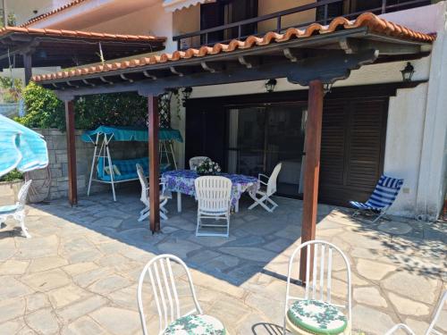 a patio with a table and chairs under a pergola at Beachfront Villa 100m from Sea for up to 10 guests in Siviri