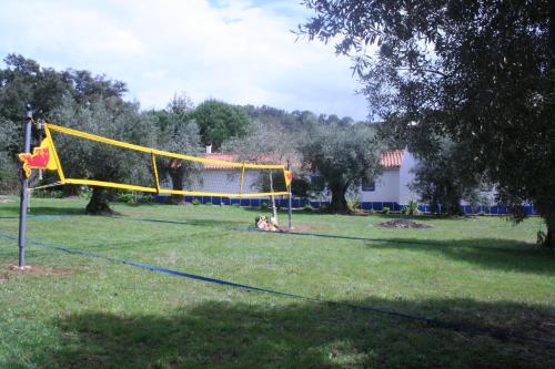 a person sitting in a field with a volleyball net at Figueirinha Ecoturismo in Montes da Estrada