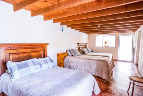 two beds in a room with wooden ceilings at Villas de Santa Ana in Manuel F. Martínez