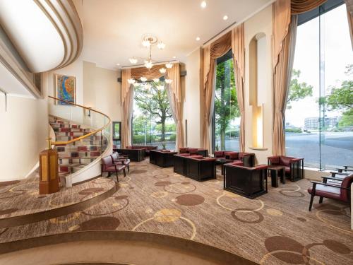 a lobby with a staircase and chairs and windows at HOTEL MYSTAYS Hiroshima Peace Park in Hiroshima