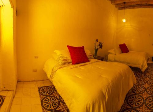a bedroom with two beds with white sheets and red pillows at Villas de Santa Ana in Manuel F. Martínez