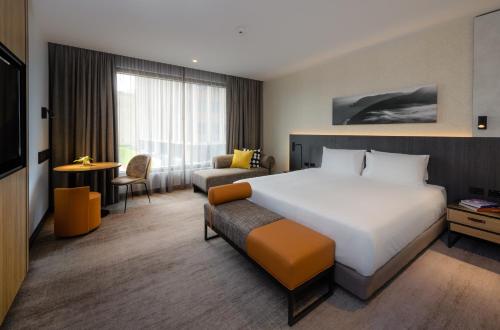 a hotel room with a large bed and a chair at Mövenpick Hotel Hobart in Hobart