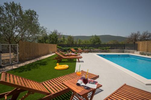 a backyard with a swimming pool with wooden tables and chairs at Apartments Brkić in Lozovac