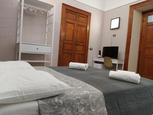 a bedroom with a bed and a desk and a television at Le Nereidi b&b Acireale Centro in Acireale