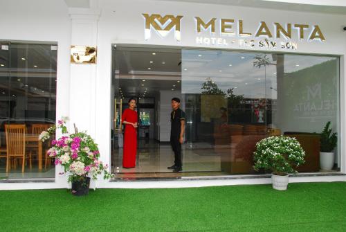 two people standing in a window of a store at Melanta Hotel - FLC Sầm Sơn in Sầm Sơn