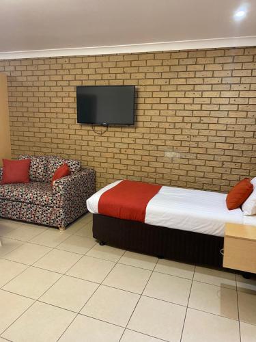a bedroom with a bed and a couch and a tv at Sunray Motor Inn in Toowoomba