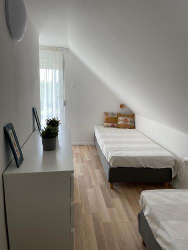 Dieses weiße Zimmer verfügt über 2 Betten, einen Schreibtisch und ein Fenster. in der Unterkunft Bogi House in Balatonfüred