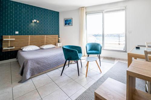 a bedroom with a bed and two chairs and a desk at Résidence Le Crystal Dinard Plage in Dinard