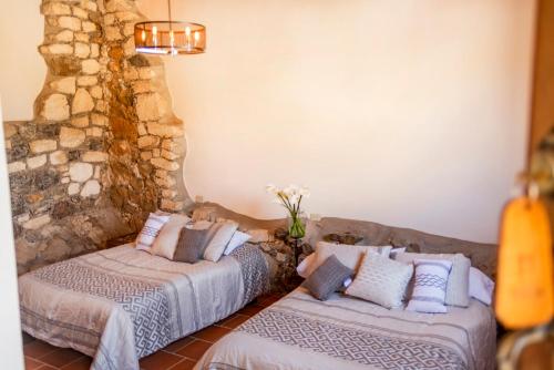 a bedroom with two beds and a stone wall at Villas de Santa Ana in Manuel F. Martínez