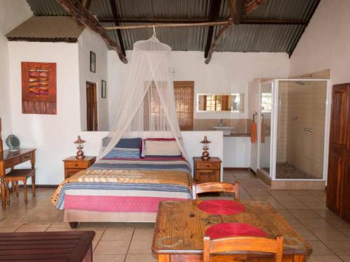 a bedroom with a bed and a table in a room at Thaba Manzi Ranch in Magaliesburg