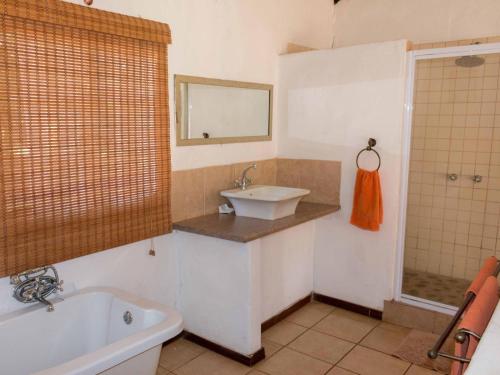 a bathroom with a sink and a tub and a mirror at Thaba Manzi Ranch in Magaliesburg