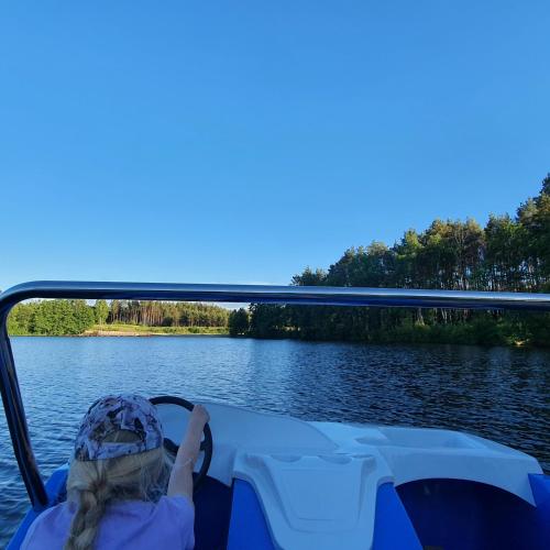 a girl is sitting on a boat on the water at Agro Breza - dom z kominkiem 20 metrow od jeziora- sauna ogrodowa in Lipusz