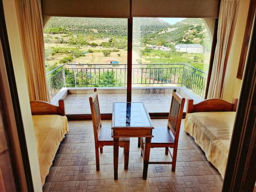 a room with a table and chairs and a large window at Flygonion Guesthouse in Kiriákion