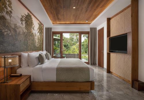 a bedroom with a large bed and a television at Adiwana Suweta in Ubud