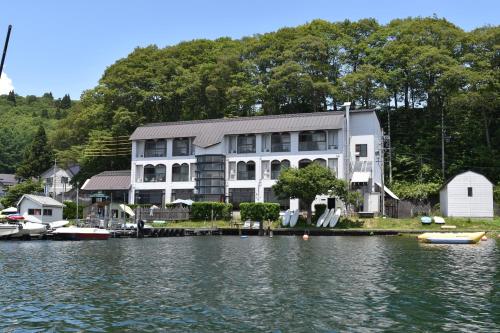 a large house on the water next to a lake at Nojiri Lake Resort in Shinano