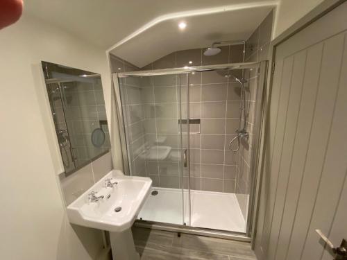 a white bathroom with a shower and a sink at Glebe Barn, Little Glebe Farm in Cheltenham