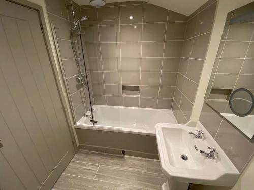 a bathroom with a sink and a bath tub at Glebe Barn, Little Glebe Farm in Cheltenham
