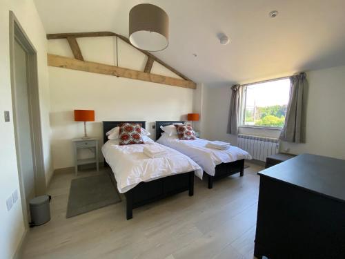 1 dormitorio con 2 camas y ventana en Glebe Barn, Little Glebe Farm, en Cheltenham