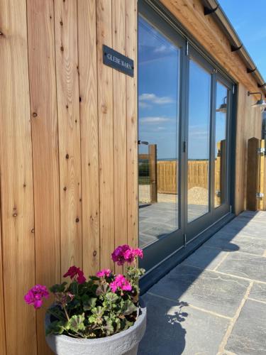 a building with a wooden wall with flowers in a pot at Glebe Barn, Little Glebe Farm in Cheltenham
