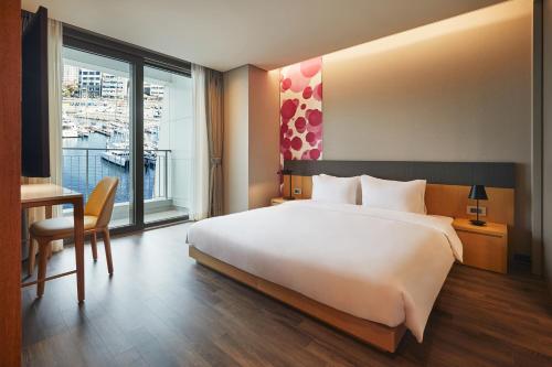 a hotel room with a bed and a desk and a window at Yeosu Belle Mer in Yeosu