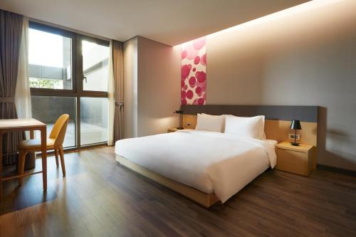 a bedroom with a large white bed and a desk at Yeosu Belle Mer in Yeosu
