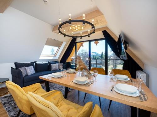 a dining room with a table and yellow chairs at Aparthotel Góralski Spa 2 in Białka Tatrzanska