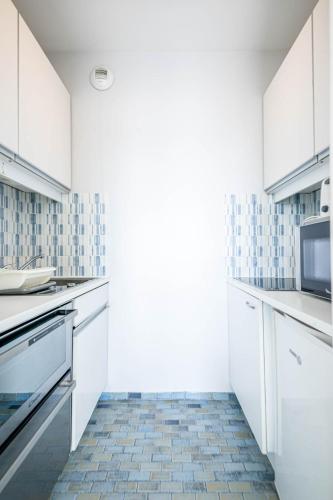 a kitchen with white cabinets and a tile floor at Résidence Le Crystal Dinard Plage in Dinard