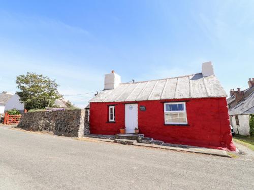 a red house with a white door on a street at Bwthyn Alarch in Haverfordwest