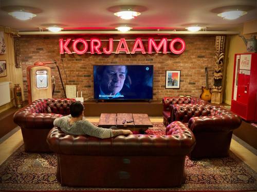 a person sitting on a couch in a room with a tv at Hotelli Verstas in Nakkila