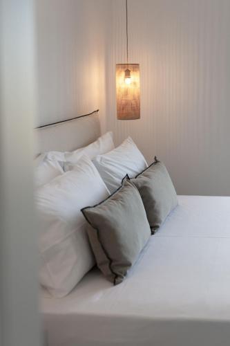 a white bed with white pillows and a light at Archon Seaside Retreat in Plaka