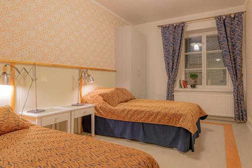 a bedroom with two beds and a desk and a window at Hotelli Verstas in Nakkila
