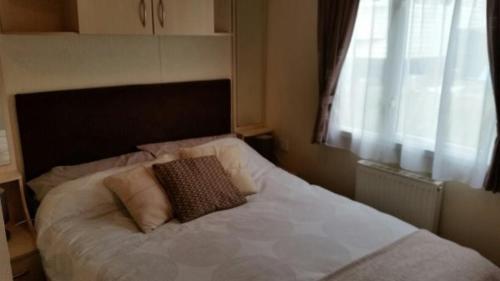 um quarto com uma cama branca e uma janela em Pine Ridge 59 Rockley Park Poole with sea view sleeps six em Poole