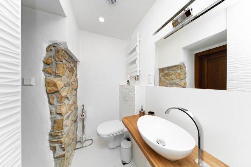 a bathroom with a sink and a stone wall at PB Apartments in Spišská Nová Ves