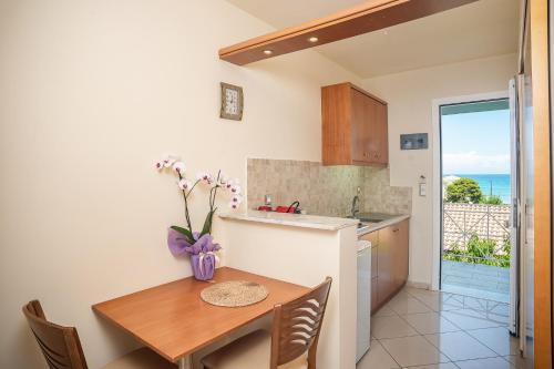 a kitchen with a table and a kitchen with a view of the ocean at Marietta Boutique Apts in Tsilivi