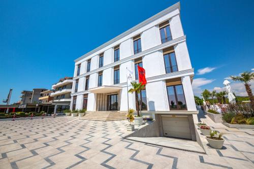 a large white building with a red flag on it at Fiore Hotel in Kavajë