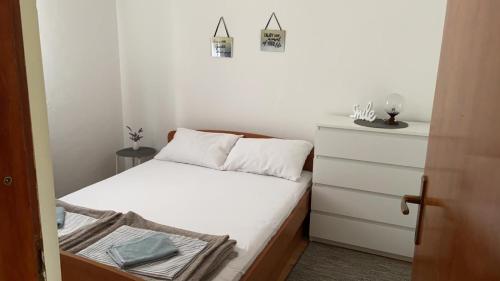a small bedroom with a bed and a dresser at Oguic apartman in Pag