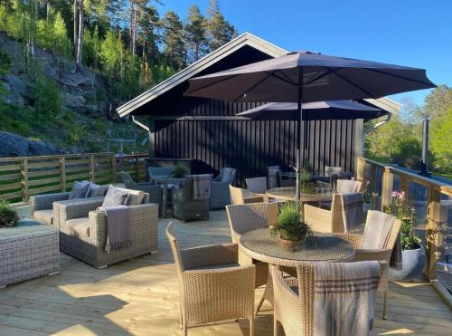 eine Terrasse mit einem Tisch, Stühlen und einem Sonnenschirm in der Unterkunft Kärrstegens Gård in Ljungskile