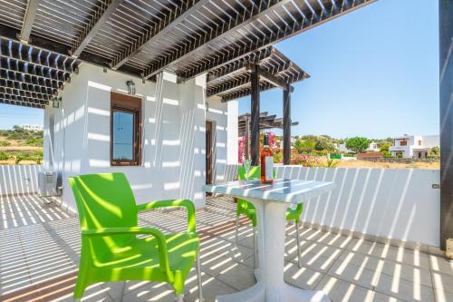 a patio with a table and green chairs at Smaragdi Beachfront Villa in Asklipiḯon